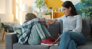 Voksen kvinne snakker med en tenåring som sitter sammenkrøpet i sofaen