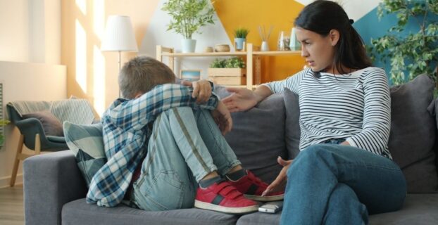 Voksen kvinne snakker med en tenåring som sitter sammenkrøpet i sofaen